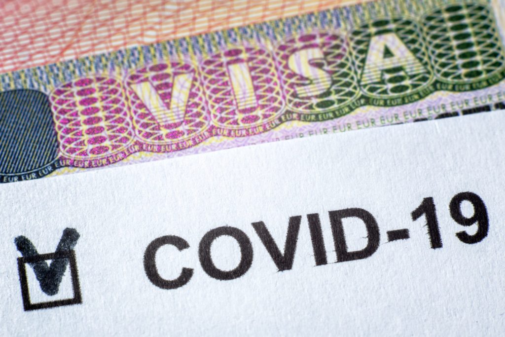 COVID-19 coronavirus pandemic and travel concept, document with COVID positive test and Visa stamp in passport.
